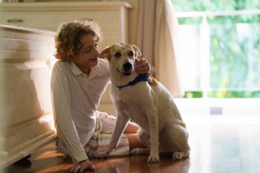 Çocuk yavru köpekle oynuyor. Çocuklar köpek yavrusuyla oynar. Küçük çocuk ve büyük köpek evde. Çocuklar ve arkadaşlık. Çocuk evcil hayvanıyla yerde oturuyor. Hayvan bakımı..