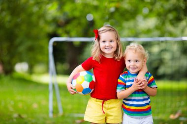 Çocuk futbol oynuyor. Çocuklar dışarıda futbol oynarlar. Küçük kız ve oğlan yaz parkında top oynuyorlar. Küçük çocuklar için sağlıklı bir aktivite. Okul spor kulübü takımı. Futbol Küçükler Ligi.