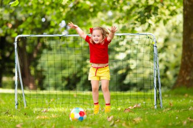 Çocuk futbol oynuyor. Çocuklar dışarıda futbol oynarlar. Küçük kız ve oğlan yaz parkında top oynuyorlar. Küçük çocuklar için sağlıklı bir aktivite. Okul spor kulübü takımı. Futbol Küçükler Ligi.