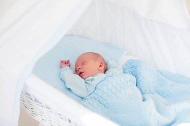 Yeni doğan bebek yatakta. Yeni doğan çocuk mavi örgü battaniye altında uyuyor. Çocuk uyku. Çocuklar için yatak takımları. Bebek yatakta uyuyor. Sağlıklı çocuk doğumdan kısa bir süre sonra. Kablo Tekstil Örme.