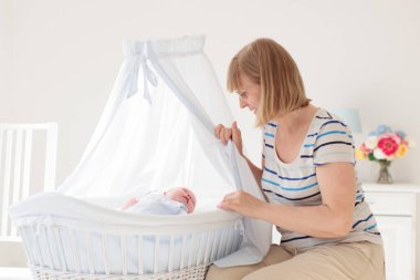 Anne ve çocuk beyaz bir yatakta. Anne ve bebek çocuk bezi güneşli yatak odasında oynarken. Ebeveyn ve çocuk evde rahatlatıcı. Aile birlikte eğleniyor. Yatak ve bebek kreş Tekstil.