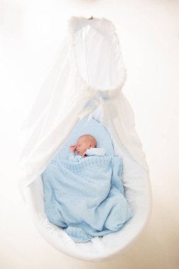 Yeni doğan bebek yatakta. Yeni doğan çocuk mavi örgü battaniye altında uyuyor. Çocuk uyku. Çocuklar için yatak takımları. Bebek yatakta uyuyor. Sağlıklı çocuk doğumdan kısa bir süre sonra. Kablo Tekstil Örme.