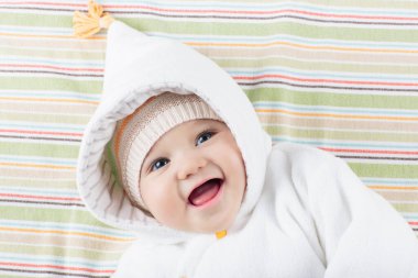 Beyaz güneşli yatak odasında sevimli bir bebek. Yeni doğmuş çocuk yatakta dinleniyor. Küçük çocuklar için çocuk odası. Çocuklar için tekstil ve yatak. Aile sabahı evde. Oyuncak ayıyla karnını doyururken doğan yeni çocuk..