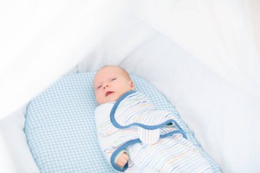 Yeni doğmuş bir çocuğu sarıp sarmalamak. Kundak battaniyeli bebek. Uyumak için sarılı ağlayan bir bebek. Yatakta aç bir bebek.
