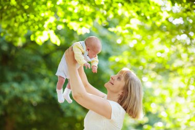 Anne yeni doğmuş bebeği parkta tutuyor. Annem ağlayan bebeği teselli ediyor. Bahçede yeni doğmuş oğlu olan bir kadın. Çocuklu aile dışarıda oynar. Ebeveynler ve çocuklar yazın eğleniyorlar..