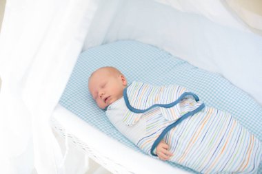 Yeni doğmuş bir çocuğu sarıp sarmalamak. Kundak battaniyeli bebek. Uyumak için sarılı ağlayan bir bebek. Yatakta aç bir bebek.