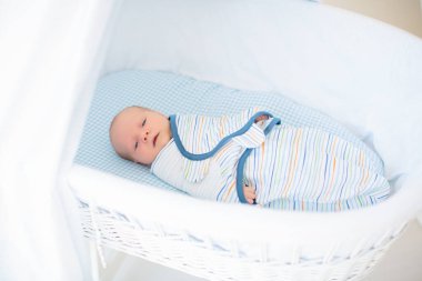 Yeni doğmuş bir çocuğu sarıp sarmalamak. Kundak battaniyeli bebek. Uyumak için sarılı ağlayan bir bebek. Yatakta aç bir bebek.