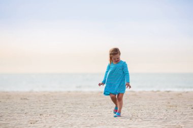 Tropik plajda oynayan çocuklar. Çocuklar yaz tatilinde yüzer ve denizde oynarlar. Kum ve su eğlencesi, küçük çocuklar için güneş koruması. Küçük bebek okyanus kıyısında koşuyor ve zıplıyor.