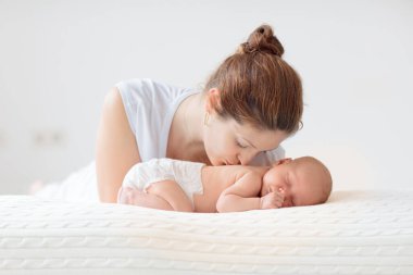 Yeni doğmuş bebeği olan genç bir anne. Annesi küçük bebeğini emziriyor. Aile evde. Çocuk bakımı. Çocukların sağlığı için emziriyorum. Küçük çocuk için beyaz yatak odası.