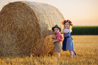 Buğday tarlasında ekmek ve krakerle bir çocuk. Almanya 'da Ekim Festivali zamanı. Geleneksel Alman kıyafetleri ve deri pantolonları içinde sonbahar hasat tarlasında çocuklar..