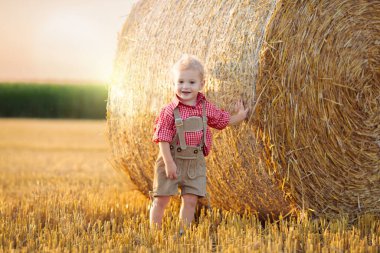 Buğday tarlasında ekmek ve krakerle bir çocuk. Almanya 'da Ekim Festivali zamanı. Geleneksel Alman kıyafetleri ve deri pantolonları içinde sonbahar hasat tarlasında çocuklar..