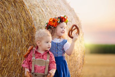 Buğday tarlasında ekmek ve krakerle bir çocuk. Almanya 'da Ekim Festivali zamanı. Geleneksel Alman kıyafetleri ve deri pantolonları içinde sonbahar hasat tarlasında çocuklar..