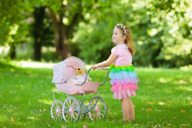 Küçük kız oyuncak bebek arabasını ayıyla itiyor. Pembe elbiseli çocuk bebek arabasıyla oynuyor. Çocukların doğum günü partisi. Çocuklar dışarıda oynar. Anne ve bebek rol yapma oyunu. Aile yaz eğlencesi. Anaokulu oyuncakları