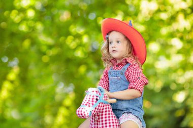 Küçük erkek ve kız kovboy ve oyuncak sallanan at Park ile oynarken cowgirl gibi giyinmiş. Çocuklar açık havada oynar. Çocuklarda Cadılar Bayramı kostümleri oyun ya da şeker. Okul öncesi veya yürümeye başlayan çocuk için oyuncaklar