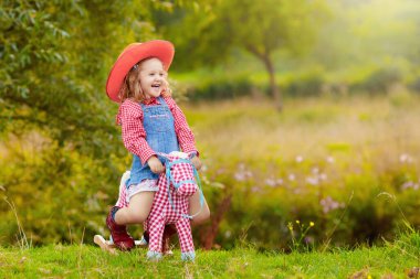 Küçük erkek ve kız kovboy ve oyuncak sallanan at Park ile oynarken cowgirl gibi giyinmiş. Çocuklar açık havada oynar. Çocuklarda Cadılar Bayramı kostümleri oyun ya da şeker. Okul öncesi veya yürümeye başlayan çocuk için oyuncaklar