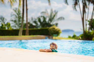 Bir grup çocuk havuza atlıyor. Yaz suyu eğlencesi. Çocuklar açık havuzda oynarlar. Genç bir çocukla yaz tatili. Tropik tatil beldesinde tatil. Çocukla seyahat et..