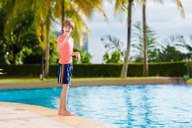 Bir grup çocuk havuza atlıyor. Yaz suyu eğlencesi. Çocuklar açık havuzda oynarlar. Genç bir çocukla yaz tatili. Tropik tatil beldesinde tatil. Çocukla seyahat et..