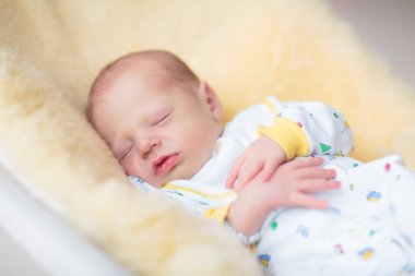 Koyun derisi battaniyenin üzerinde sevimli bir bebek. Yeni doğmuş çocuk yatakta dinleniyor. Küçük çocuklar için çocuk odası. Çocuklar için tekstil ve yatak. Aile sabahı evde. Yeni doğan bebekler için kış giysileri.