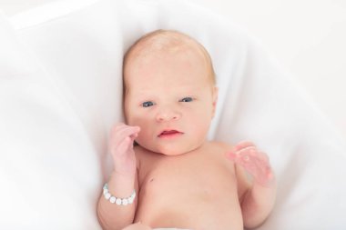 Beyaz güneşli yatak odasında sevimli bir bebek. Yeni doğmuş çocuk yatakta dinleniyor. Küçük çocuklar için çocuk odası. Çocuklar için tekstil ve yatak. Aile sabahı evde. Oyuncak ayıyla karnını doyururken doğan yeni çocuk..