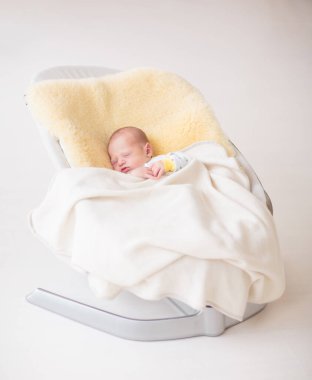 Koyun derisi battaniyenin üzerinde sevimli bir bebek. Yeni doğmuş çocuk yatakta dinleniyor. Küçük çocuklar için çocuk odası. Çocuklar için tekstil ve yatak. Aile sabahı evde. Yeni doğan bebekler için kış giysileri.