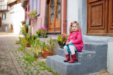 Soğuk bir sonbahar günü, tarihi ortaçağ şehir merkezinde sokakta yürüyen çocuklar. Eguisheim, Alsace, Fransa 'da sonbahar tatili sırasında. Çocuklarla seyahat ve turizm.