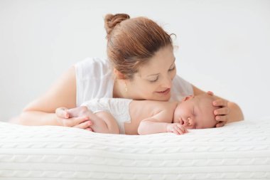 Yeni doğmuş bebeği olan genç bir anne. Annesi küçük bebeğini emziriyor. Aile evde. Çocuk bakımı. Çocukların sağlığı için emziriyorum. Küçük çocuk için beyaz yatak odası.