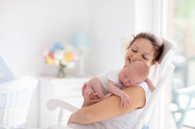 Yeni doğmuş bebeği olan genç bir anne. Annesi küçük bebeğini emziriyor. Aile evde. Çocuk bakımı. Çocukların sağlığı için emziriyorum. Küçük çocuk için beyaz yatak odası.