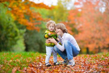 Mutlu çocuklar oyun sonbahar günü sıcak güneşli güzel sonbahar Park'ta. Çocuklar oyun altın akçaağaç yaprakları ile.