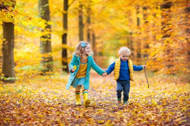 Mutlu çocuklar oyun sonbahar günü sıcak güneşli güzel sonbahar Park'ta. Çocuklar oyun altın akçaağaç yaprakları ile.