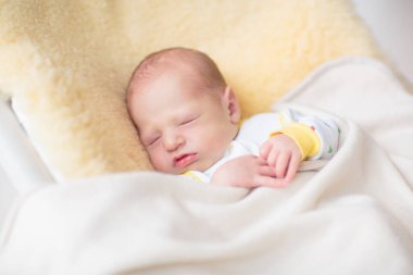 Koyun derisi battaniyenin üzerinde sevimli bir bebek. Yeni doğmuş çocuk yatakta dinleniyor. Küçük çocuklar için çocuk odası. Çocuklar için tekstil ve yatak. Aile sabahı evde. Yeni doğan bebekler için kış giysileri.