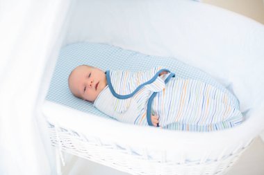 Yeni doğmuş bir çocuğu sarıp sarmalamak. Kundak battaniyeli bebek. Uyumak için sarılı ağlayan bir bebek. Yatakta aç bir bebek.