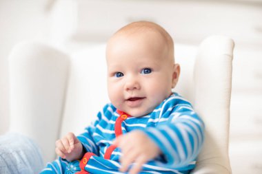 Beyaz güneşli yatak odasında sevimli bir bebek. Yeni doğmuş çocuk yatakta dinleniyor. Küçük çocuklar için çocuk odası. Çocuklar için tekstil ve yatak. Aile sabahı evde. Oyuncak ayıyla karnını doyururken doğan yeni çocuk..