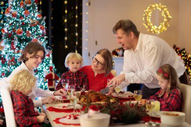 Çocuklu bir aile şöminede hindi yiyor ve Noel ağacı süslüyor. Aileler, dedeler ve çocuklar şenlik yemeğine. Kış tatili kutlaması ve yemek. Çocuklar hediyeleri açar.