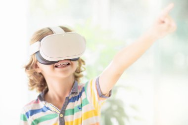 Sanal gerçeklik gözlüklü çocuk. Çocuklar için video kayıt seti. Küçük çocuk bilgisayar oyunu oynuyor. Modern dijital cihazla öğreniyorum. Çocuklar elektronik aletlerle ders çalışırlar. Gelecek eğitim konsepti. Eğlenceli oyun..