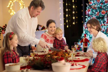 Çocuklu bir aile şöminede hindi yiyor ve Noel ağacı süslüyor. Aileler, dedeler ve çocuklar şenlik yemeğine. Kış tatili kutlaması ve yemek. Çocuklar hediyeleri açar.