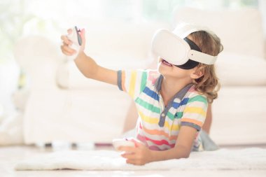 Sanal gerçeklik gözlüklü çocuk. Çocuklar için video kayıt seti. Küçük çocuk bilgisayar oyunu oynuyor. Modern dijital cihazla öğreniyorum. Çocuklar elektronik aletlerle ders çalışırlar. Gelecek eğitim konsepti. Eğlenceli oyun..