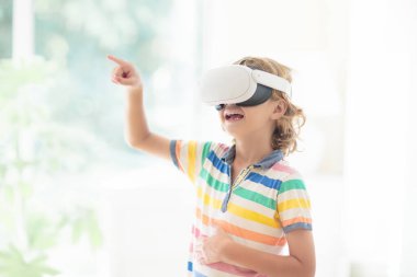 Sanal gerçeklik gözlüklü çocuk. Çocuklar için video kayıt seti. Küçük çocuk bilgisayar oyunu oynuyor. Modern dijital cihazla öğreniyorum. Çocuklar elektronik aletlerle ders çalışırlar. Gelecek eğitim konsepti. Eğlenceli oyun..