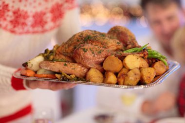 Çocuklu bir aile şöminede hindi yiyor ve Noel ağacı süslüyor. Aileler, dedeler ve çocuklar şenlik yemeğine. Kış tatili kutlaması ve yemek. Çocuklar hediyeleri açar.