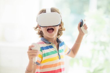 Sanal gerçeklik gözlüklü çocuk. Çocuklar için video kayıt seti. Küçük çocuk bilgisayar oyunu oynuyor. Modern dijital cihazla öğreniyorum. Çocuklar elektronik aletlerle ders çalışırlar. Gelecek eğitim konsepti. Eğlenceli oyun..