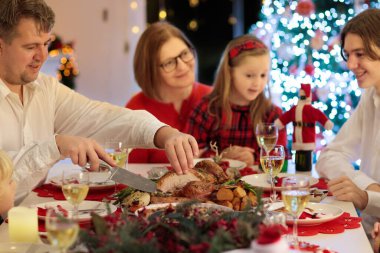 Çocuklu bir aile şöminede hindi yiyor ve Noel ağacı süslüyor. Aileler, dedeler ve çocuklar şenlik yemeğine. Kış tatili kutlaması ve yemek. Çocuklar hediyeleri açar.