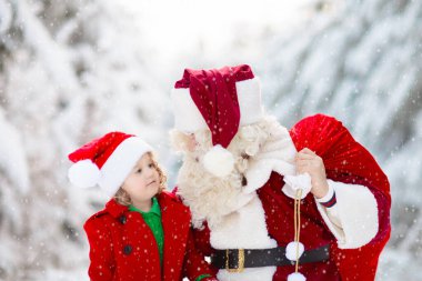 Karlı ormanda Noel hediyeli çocuklar ve Noel Baba. Çocuklar kar parkında Noel Baba 'ya yardım ediyor. Eğlenceli kızak gezisi. Noel tatili eğlencesi. Noel Baba hediyeler ve elflerle. Kış tatili.