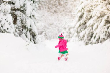 Çocuklar kışın karla oynuyorlar. Renkli ceketli küçük bir kız ve Noel 'de kış parkında kızağa binen örgü şapkalı bir kız. Çocuklar karlı ormanda kızak kullanırdı. Çocuklar için Sledge biniciliği.