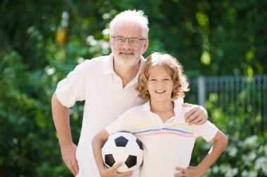 Dedem ve çocuklar güneşli bahçede. Mutlu aile yaz parkında futbol oynuyor. Büyükbaba ve çocuklar futbol oynarlar. Nesil aşkı. Aktif kıdemli adam ve küçük çocuk. Torunlar dedeleri ziyaret ediyor..