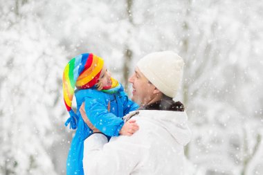 Çocuklar kış parkında karda oynarlar. Çocuklar karlı soğuk bir günde dışarıda oynuyorlar. Oğlan ve kız kızakla gezerken eğleniyorlar. Noel tatili aktivitesi. Kış havasında açık hava eğlencesi. Çocukla seyahat et..