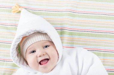 Beyaz güneşli yatak odasında sevimli bir bebek. Yeni doğmuş çocuk yatakta dinleniyor. Küçük çocuklar için çocuk odası. Çocuklar için tekstil ve yatak. Aile sabahı evde. Oyuncak ayıyla karnını doyururken doğan yeni çocuk..