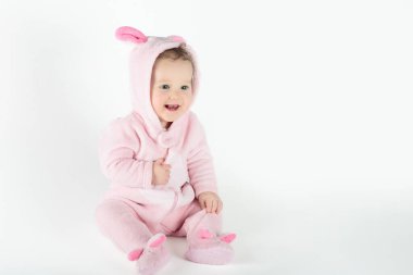 Beyaz güneşli yatak odasında sevimli bir bebek. Yeni doğmuş çocuk yatakta dinleniyor. Küçük çocuklar için çocuk odası. Çocuklar için tekstil ve yatak. Aile sabahı evde. Oyuncak ayıyla karnını doyururken doğan yeni çocuk..