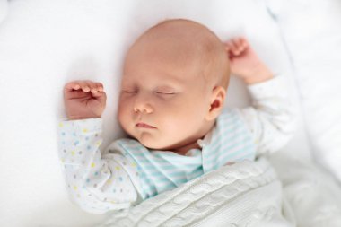 Yeni doğan bebek yatakta. Yeni doğan çocuk beyaz örgü battaniye altında uyuyor. Çocuk uyku. Çocuklar için yatak takımları. Bebek yatakta uyuyor. Sağlıklı çocuk doğumdan kısa bir süre sonra. Kablo Tekstil Örme.