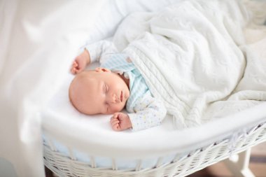 Yeni doğan bebek yatakta. Yeni doğan çocuk beyaz örgü battaniye altında uyuyor. Çocuk uyku. Çocuklar için yatak takımları. Bebek yatakta uyuyor. Sağlıklı çocuk doğumdan kısa bir süre sonra. Kablo Tekstil Örme.