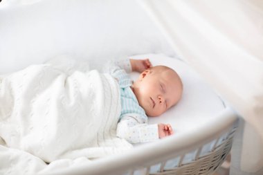Yeni doğan bebek yatakta. Yeni doğan çocuk beyaz örgü battaniye altında uyuyor. Çocuk uyku. Çocuklar için yatak takımları. Bebek yatakta uyuyor. Sağlıklı çocuk doğumdan kısa bir süre sonra. Kablo Tekstil Örme.