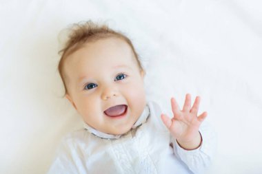 Beyaz güneşli yatak odasında sevimli bir bebek. Yeni doğmuş çocuk yatakta dinleniyor. Küçük çocuklar için çocuk odası. Çocuklar için tekstil ve yatak. Aile sabahı evde. Örgü kazaklı çocuk..